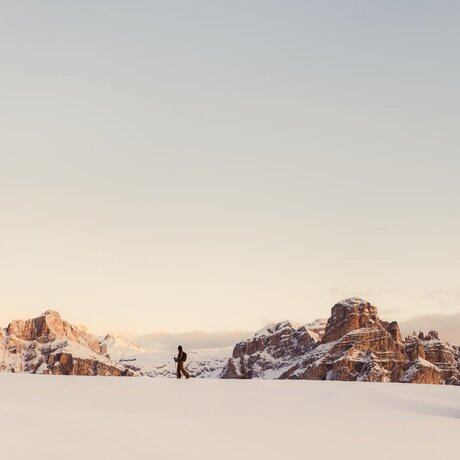 Skier touring across snow-covered Alpine landscape at Aman Rosa Alpina, Italy.