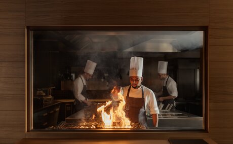 Fireplace with glowing flames at Aman Rosa Alpina, Italy, The Grill dining venue.