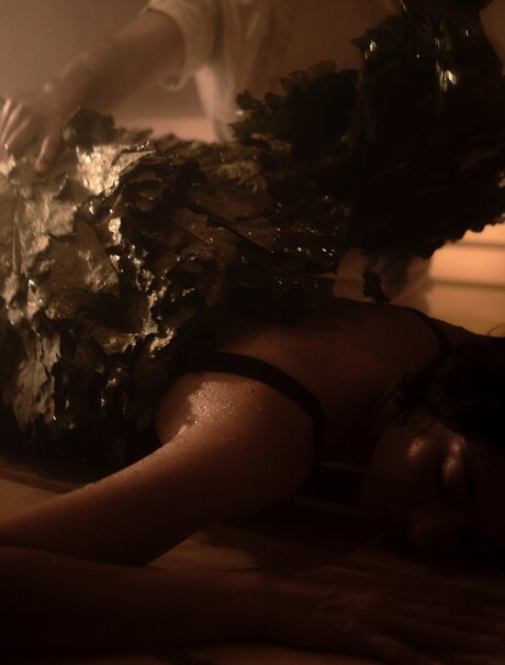 Spa therapist applying dark mineral treatment to guest's back at Amanvari's wellness facility.