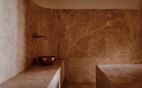 Amanvari spa hammam with terracotta-tiled walls and stone bench seating.