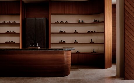Amanvari spa entrance with wooden reception desk and shelving displaying wellness products.