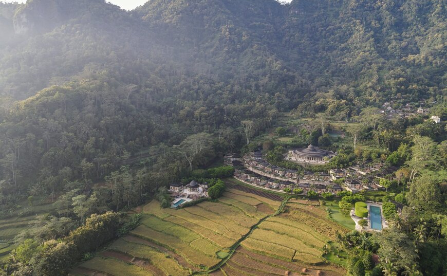 Aerial view of Amanjiwo nestled among verdant valleys and rice terraces in Indonesia.