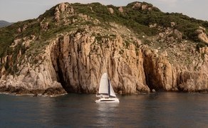 Sailing catamaran anchored off dramatic basalt cliffs at Amanoi, Vietnam.