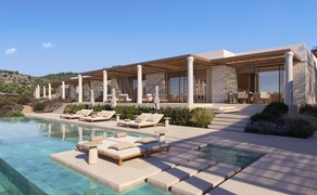 アマンゾイ リゾートのプール施設。日中の陽光が柱のある現代建築を照らし、ウッドデッキとサンベッドが水辺に配置されている。