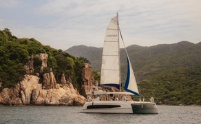 Catamaran sailing past limestone cliffs at Amanoi, Vietnam.