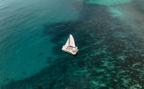 Aerial view of a white catamaran anchored in turquoise waters off Amanoi, Vietnam.
