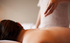 Amanoi Resort spa treatment, therapist's hands performing a massage on a guest's back.