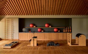 Amanoi pilates studio with wooden slat ceiling, studio equipment, and colourful exercise balls arranged on wall shelving.