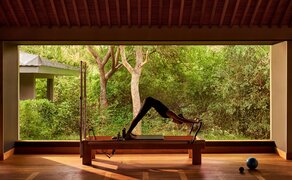 Pilates studio at Amanoi resort with wooden flooring, large windows overlooking tropical gardens, and exercise equipment positioned for practice.