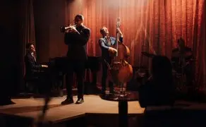Músicos tocam jazz em palco com cortinas vermelhas no Aman New York.