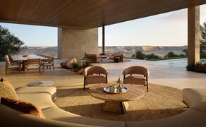 Living room at Amansamar with curved seating arrangement overlooking water and mountains.