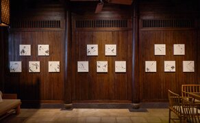 Side hall exhibition display at Amanfayun featuring framed artworks arranged on wooden panels.