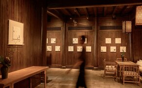 Artist exhibition display at Amanfayun with illuminated wall alcoves and wooden furnishings.