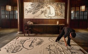 Artist at work on intricate floor installation during Amanfayun on-site creation exhibition.