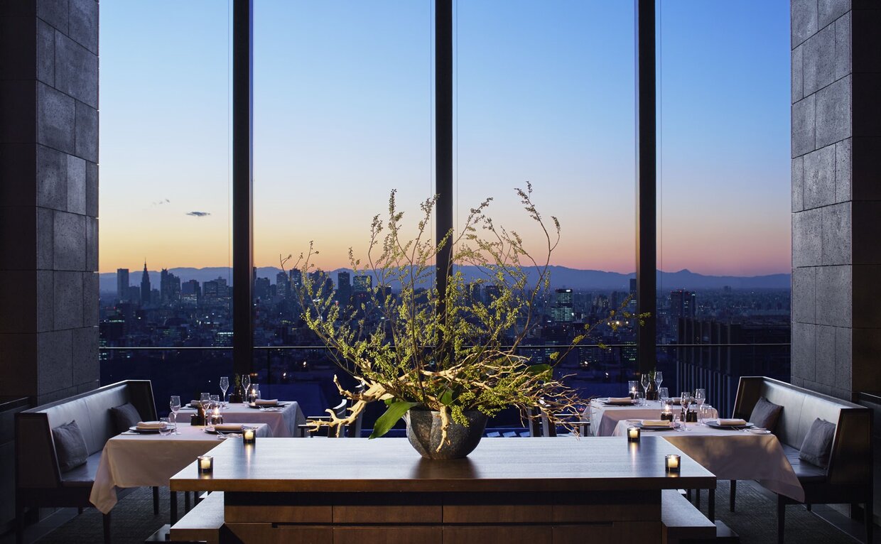 Dining table at Aman Tokyo with panoramic views of Tokyo's skyline at dusk.