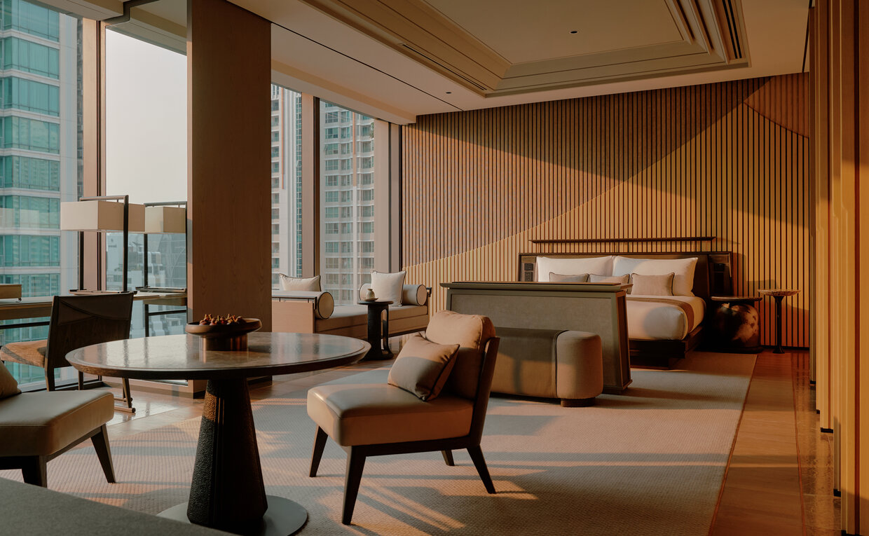 Spacious principal bedroom at Aman Nai Lert Bangkok with warm wood panelling, floor-to-ceiling windows, and contemporary furnishings.