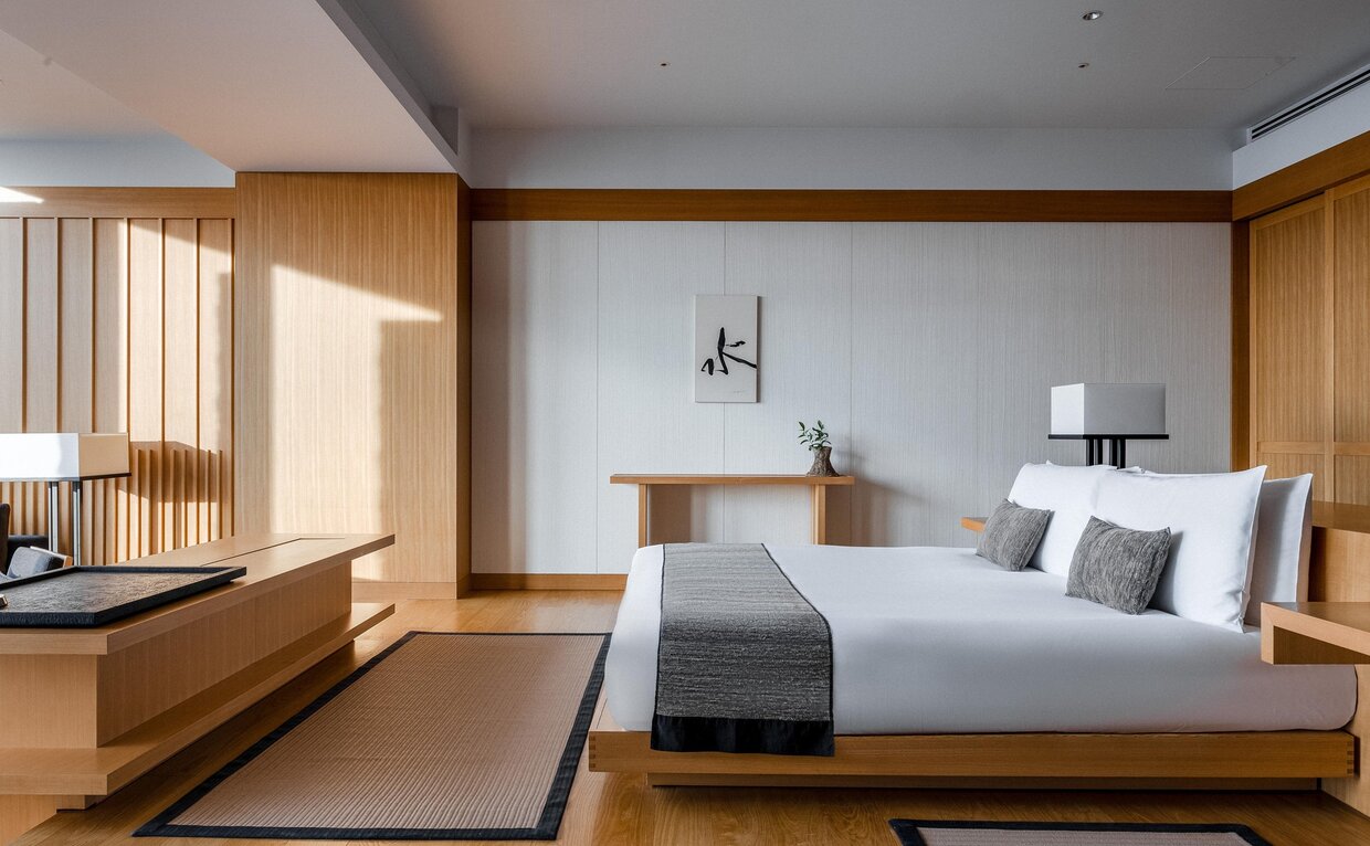 Deluxe Room at Aman Tokyo with wooden furnishings, serene white and grey palette, and contemporary Japanese design.