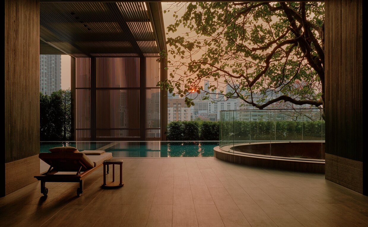 Spa relaxation area at Aman Nai Lert Bangkok overlooking the swimming pool and gardens at dusk.