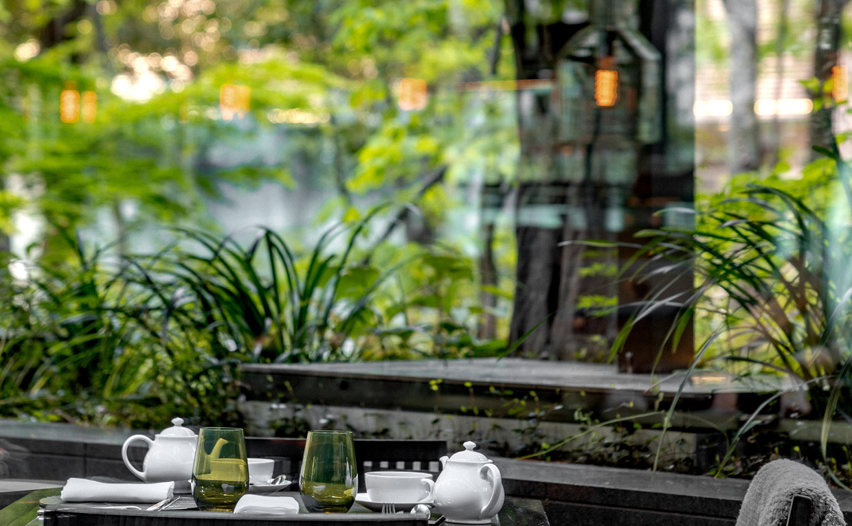 Café garden at Aman Tokyo with lush plants and outdoor seating overlooking verdant surroundings.