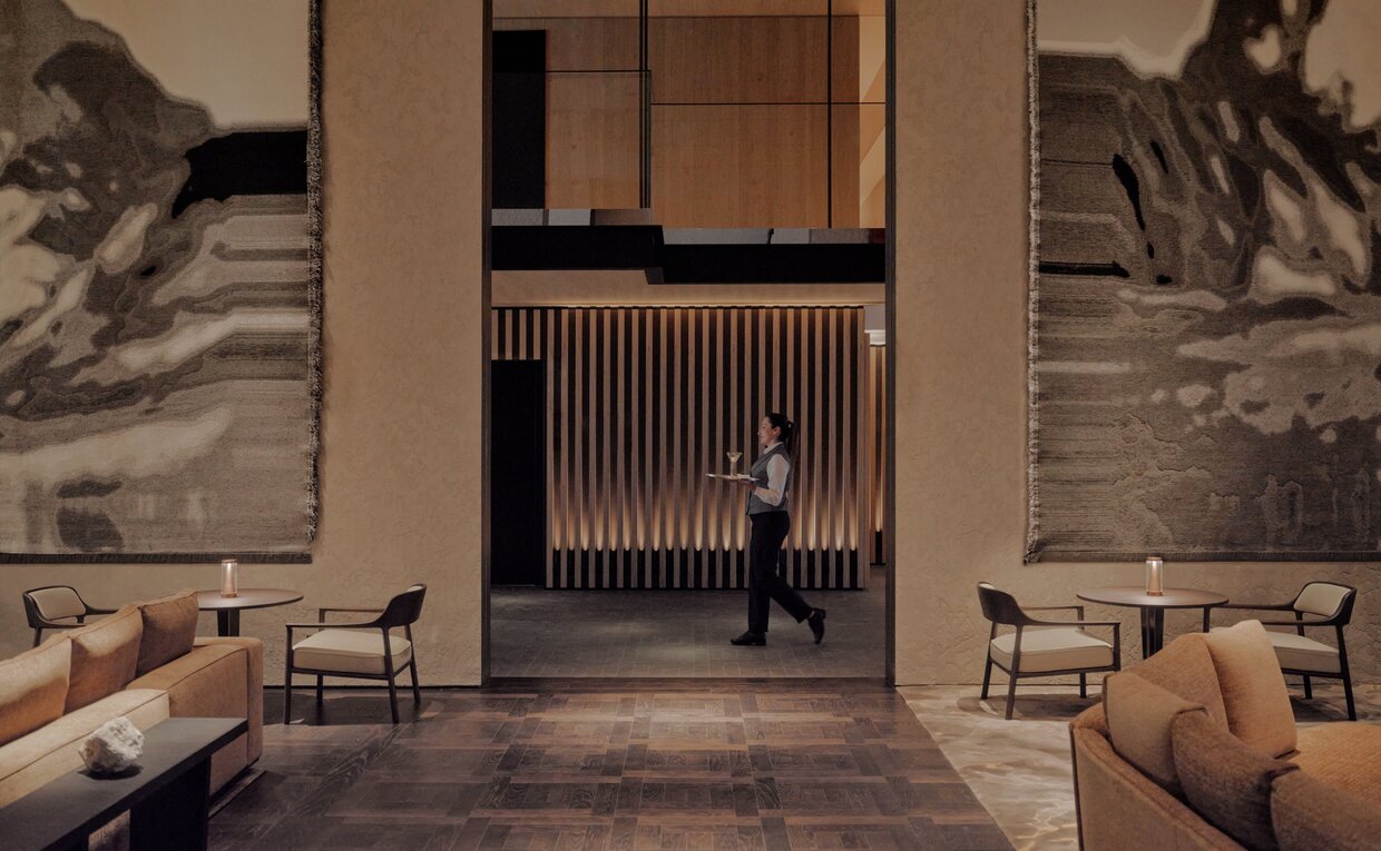 Entrance hall at Aman Rosa Alpina with seated figures and large-scale landscape photographs on walls.