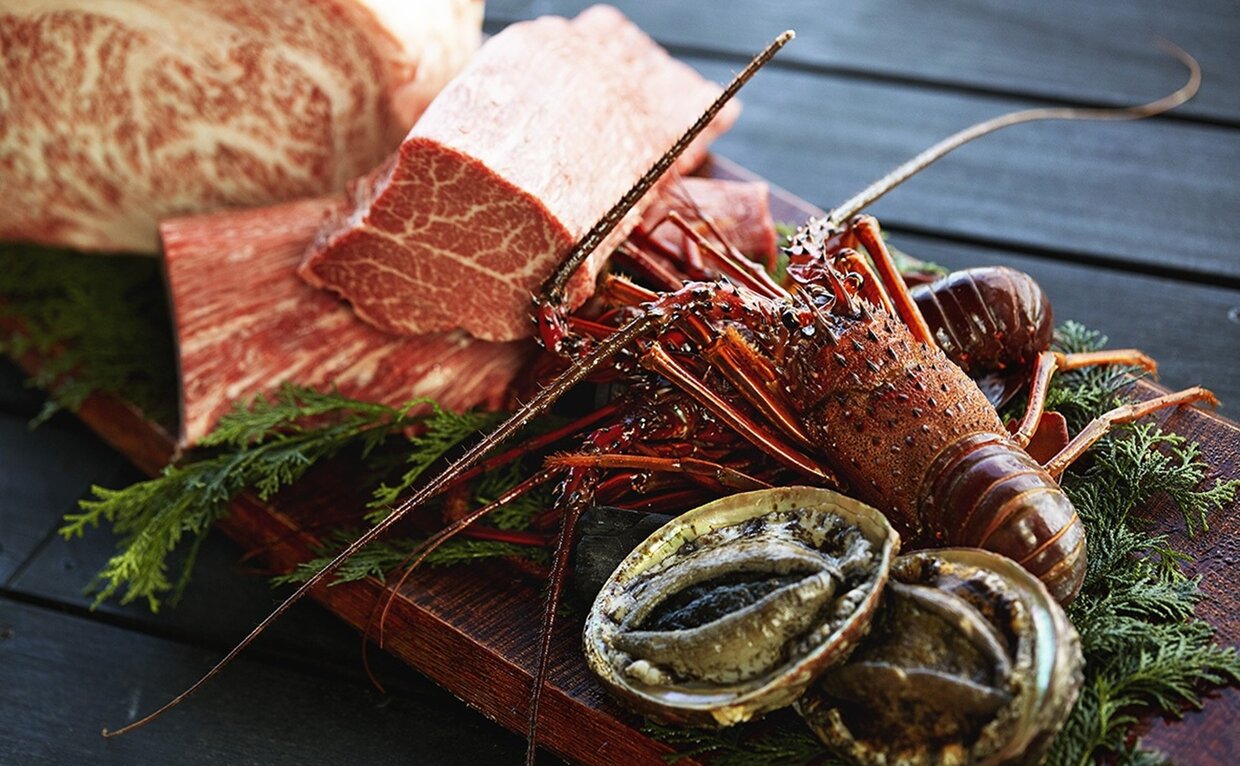 Fresh lobster and sliced fish arranged on dark slate at Amanemu's dining venue.