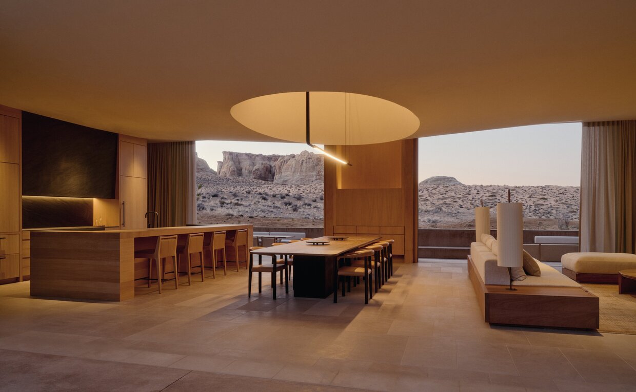 Sala living e dining della villa con sei camere da letto ad Amangiri resort, con pareti in legno caldo, mobili moderni e vista sul paesaggio desertico.