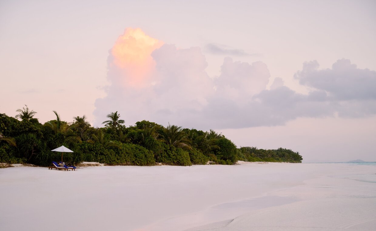 Amanpulo's forested island emerging from calm waters at dusk, Philippines.