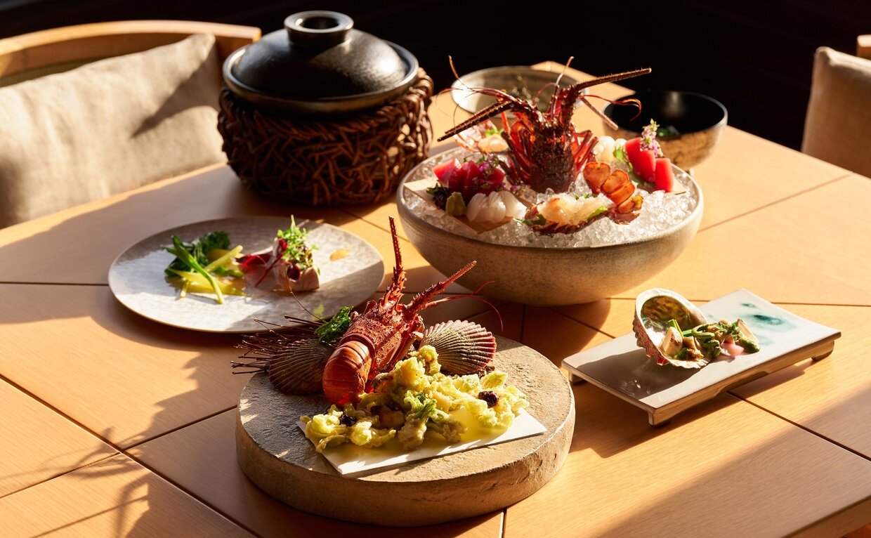 Amanemu's 10th anniversary dining spread featuring multiple plates of Japanese cuisine arranged on a wooden table with natural light.