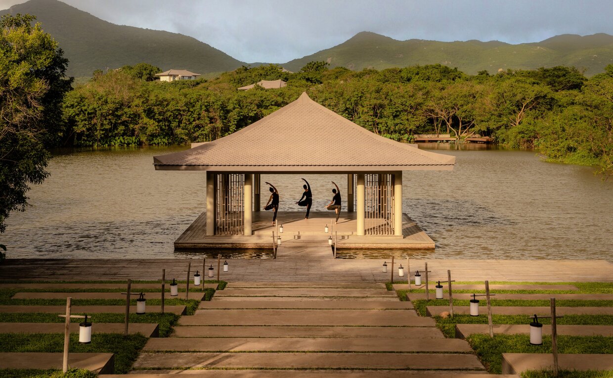 安缦诺怡度假村的瑜伽馆，米色八角亭坐落于木质平台，周围是山景和绿地。