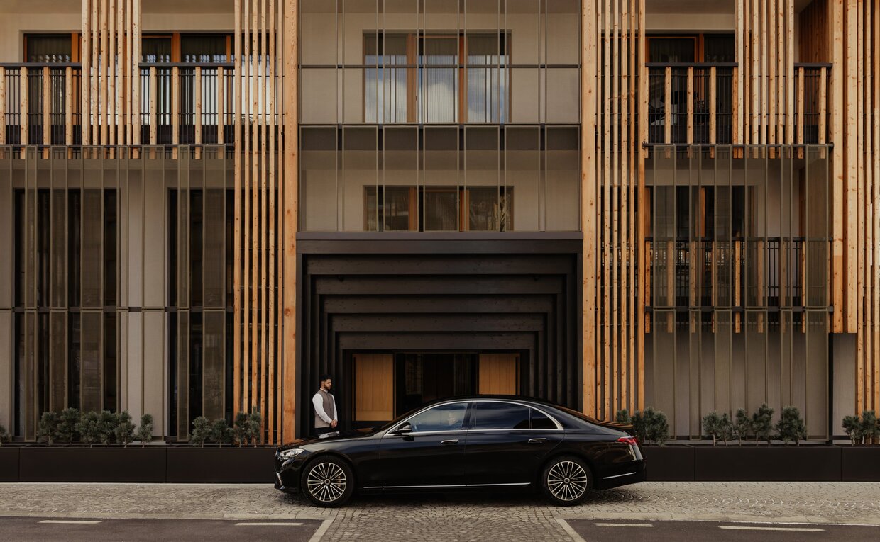 Ingresso principale di Aman Rosa Alpina, auto parcheggiata davanti alla facciata in legno della struttura.