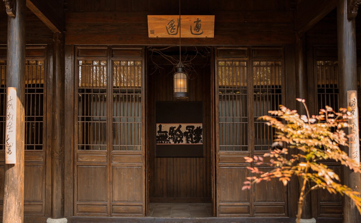 Wooden entrance doors at Amanfayun with illuminated golden tree and traditional Chinese characters above doorway.