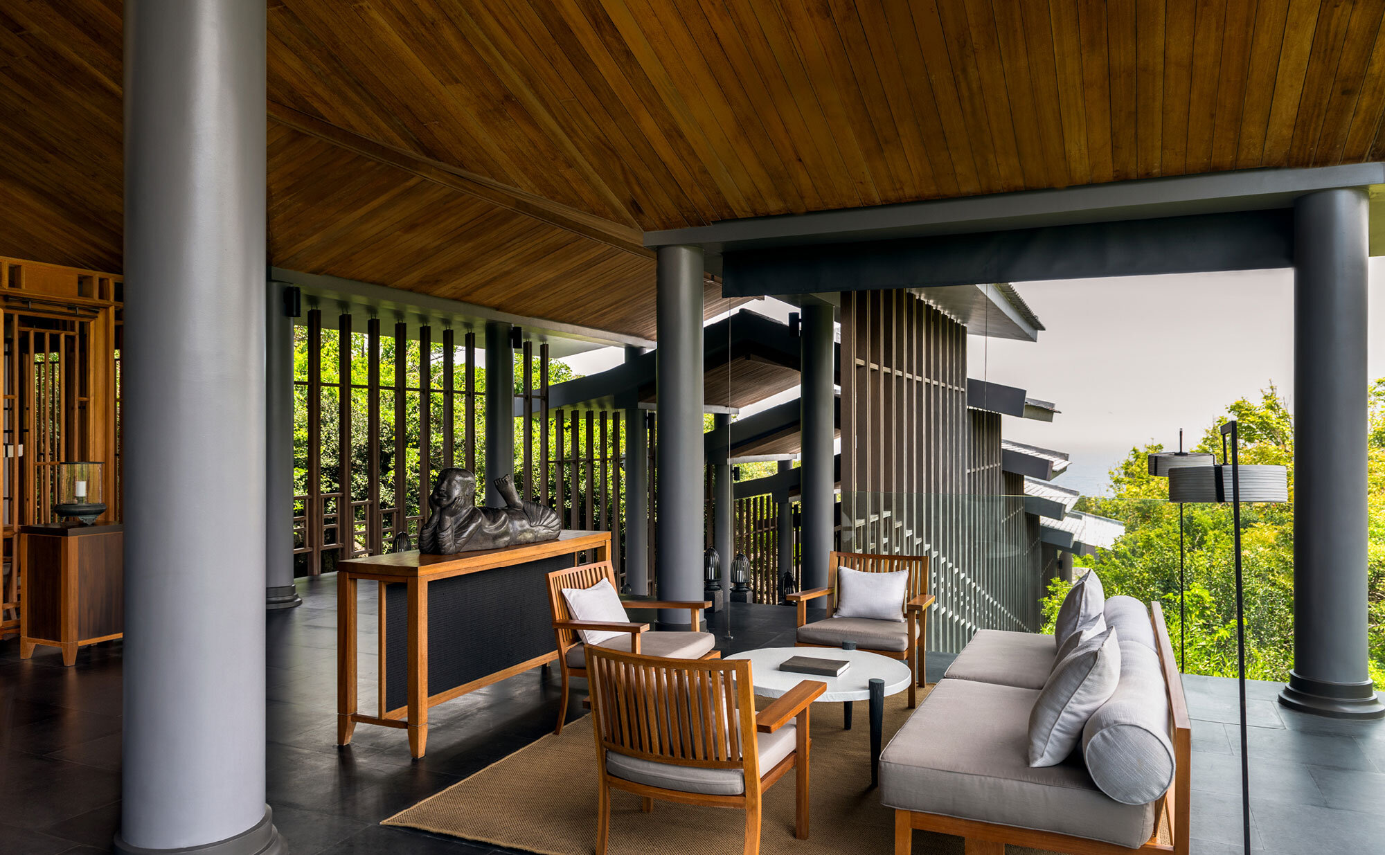 Amanoi resort : pavillon en plein air avec mobilier en bois surplombant un paysage verdoyant, colonnes encadrant la vue.