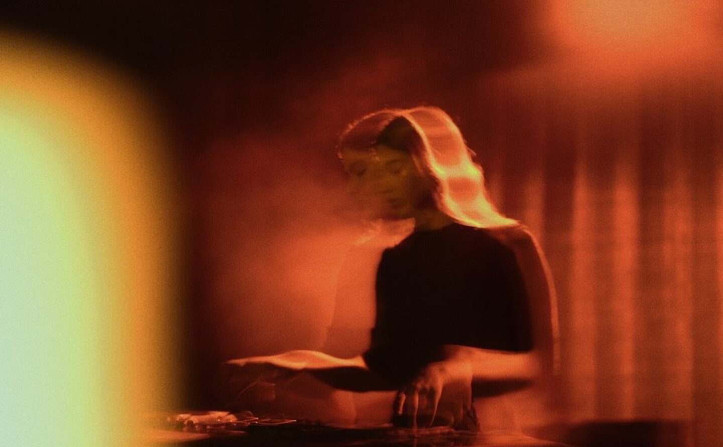 DJ performing at The Jazz Club, Aman New York, with warm amber lighting and musical equipment.