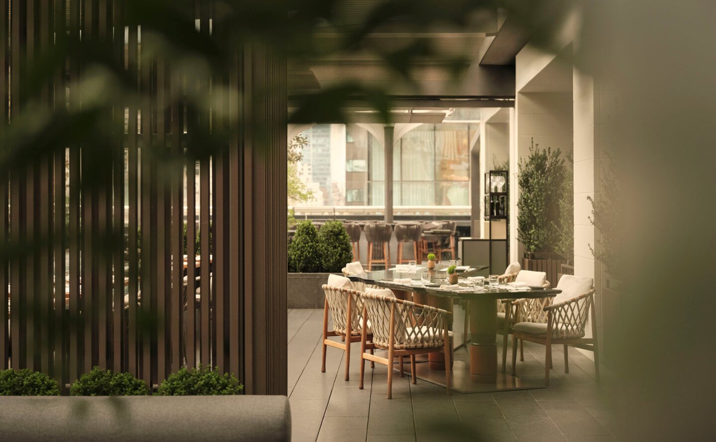Garden terrace dining venue at Aman New York with wooden screens and natural light.