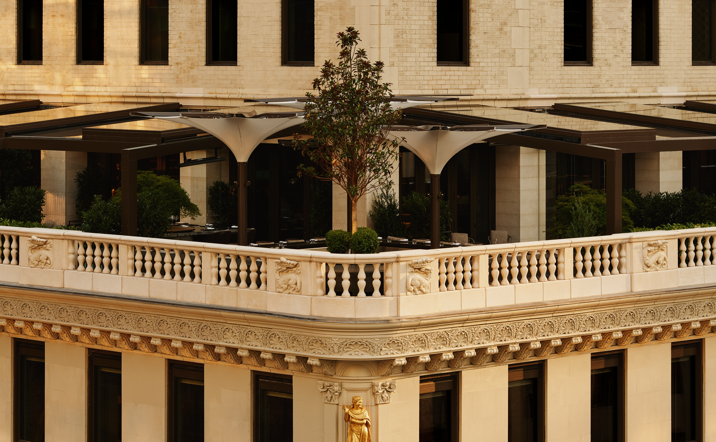 Exterior view of Aman New York's garden terrace with classical stone balustrade and arched colonnade.