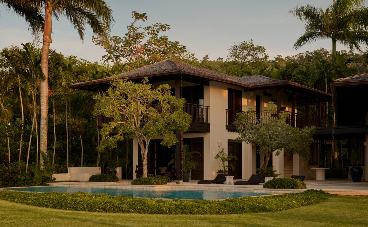 Amanera villa nestled among palm trees with manicured lawn in Dominican Republic.