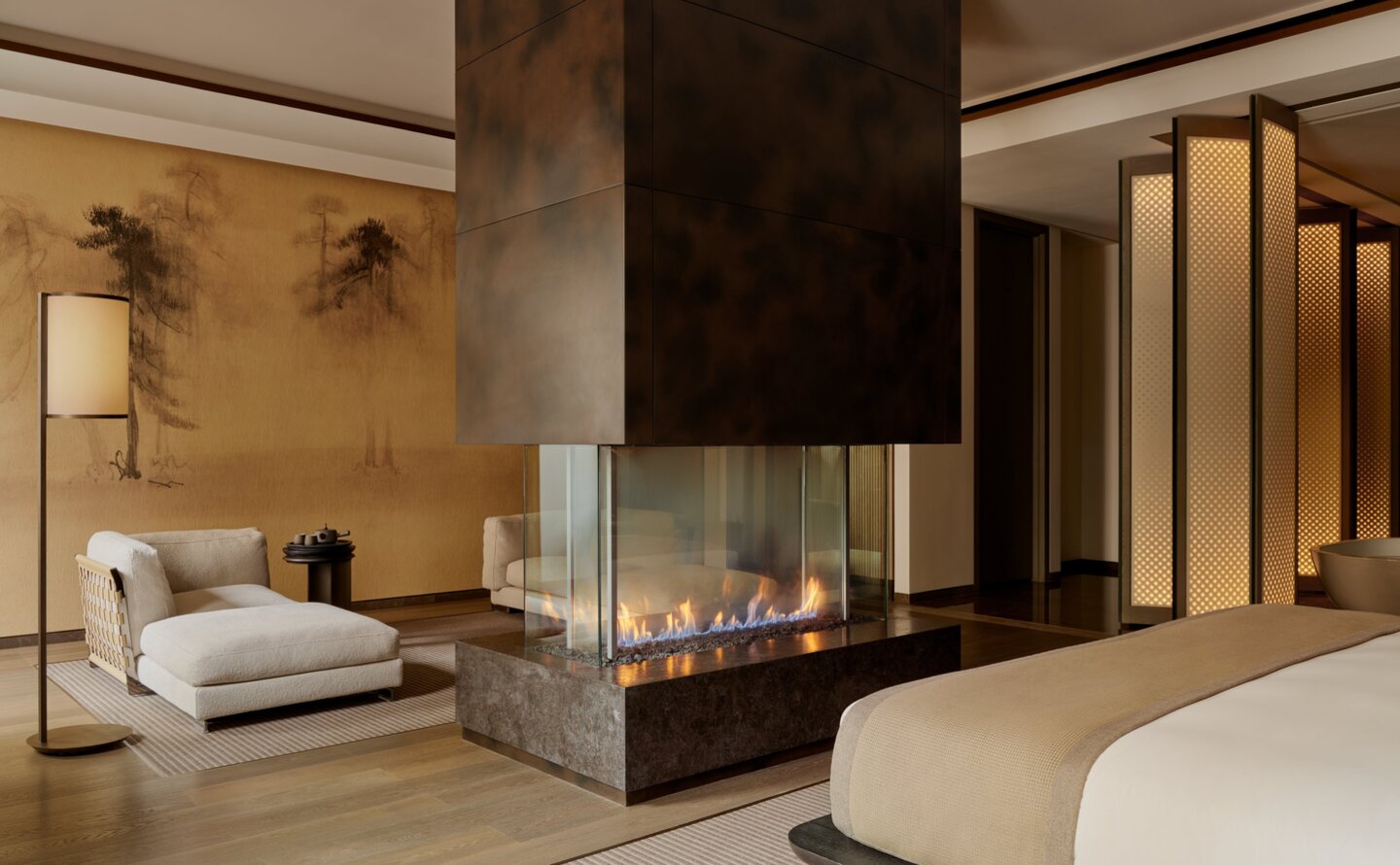 Grand Suite at Aman New York with fireplace, seating area and bed.
