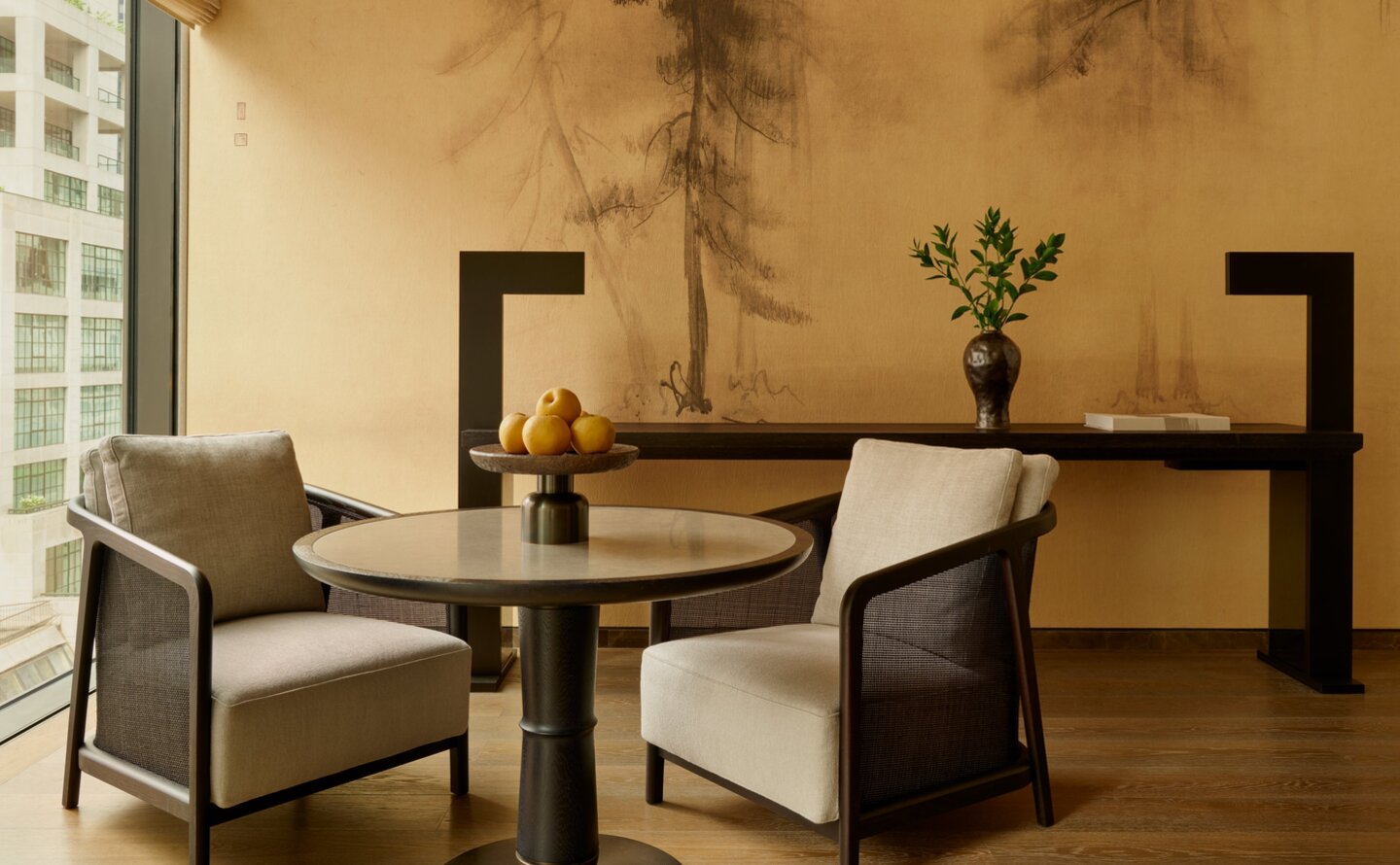 Premier Suite sitting area at Aman New York, with two chairs and low table beneath a sculptural wall installation.