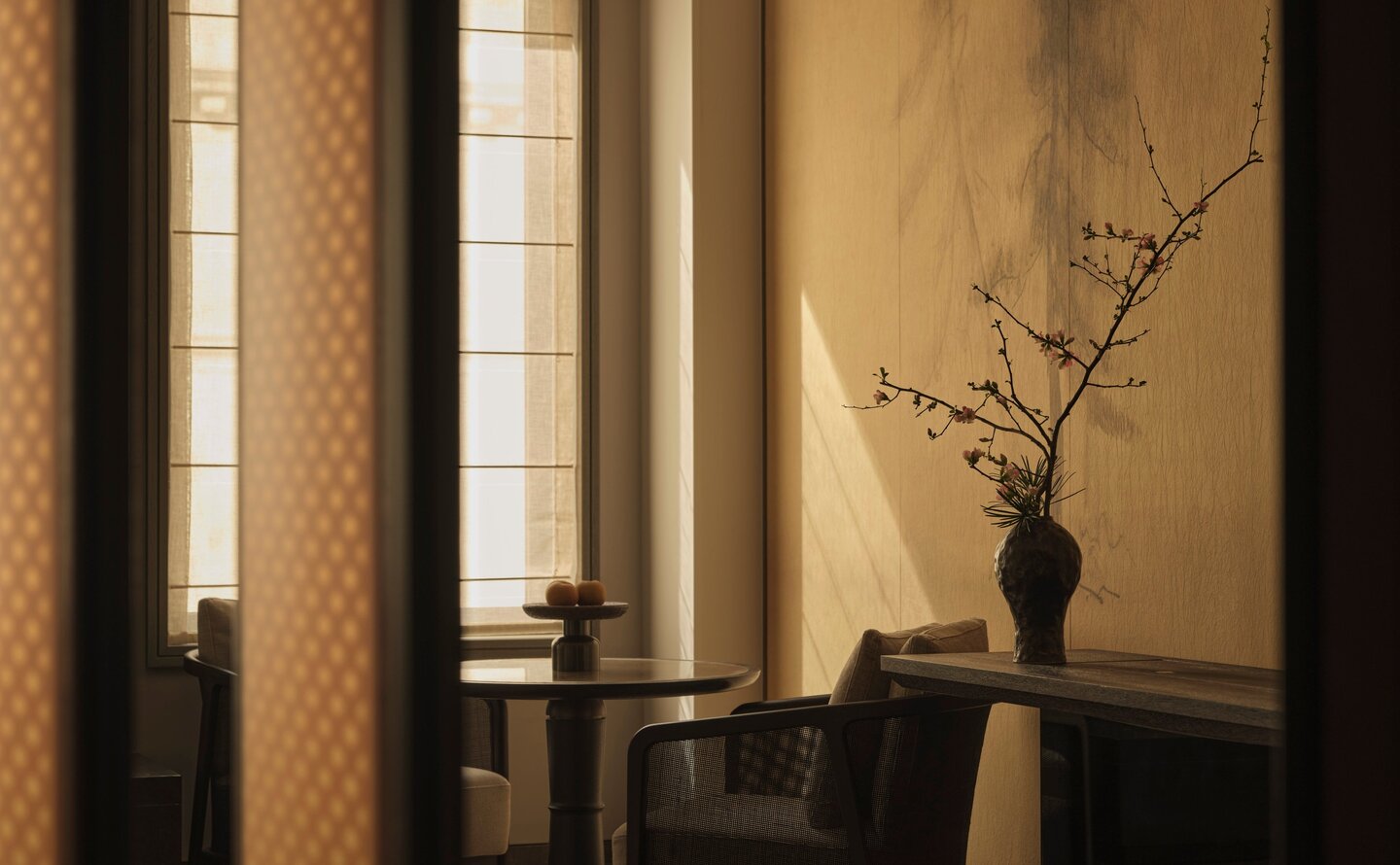 Premier Suite entrance at Aman New York, featuring a dark wood floor, cream walls, and minimalist decor with a solitary vase.