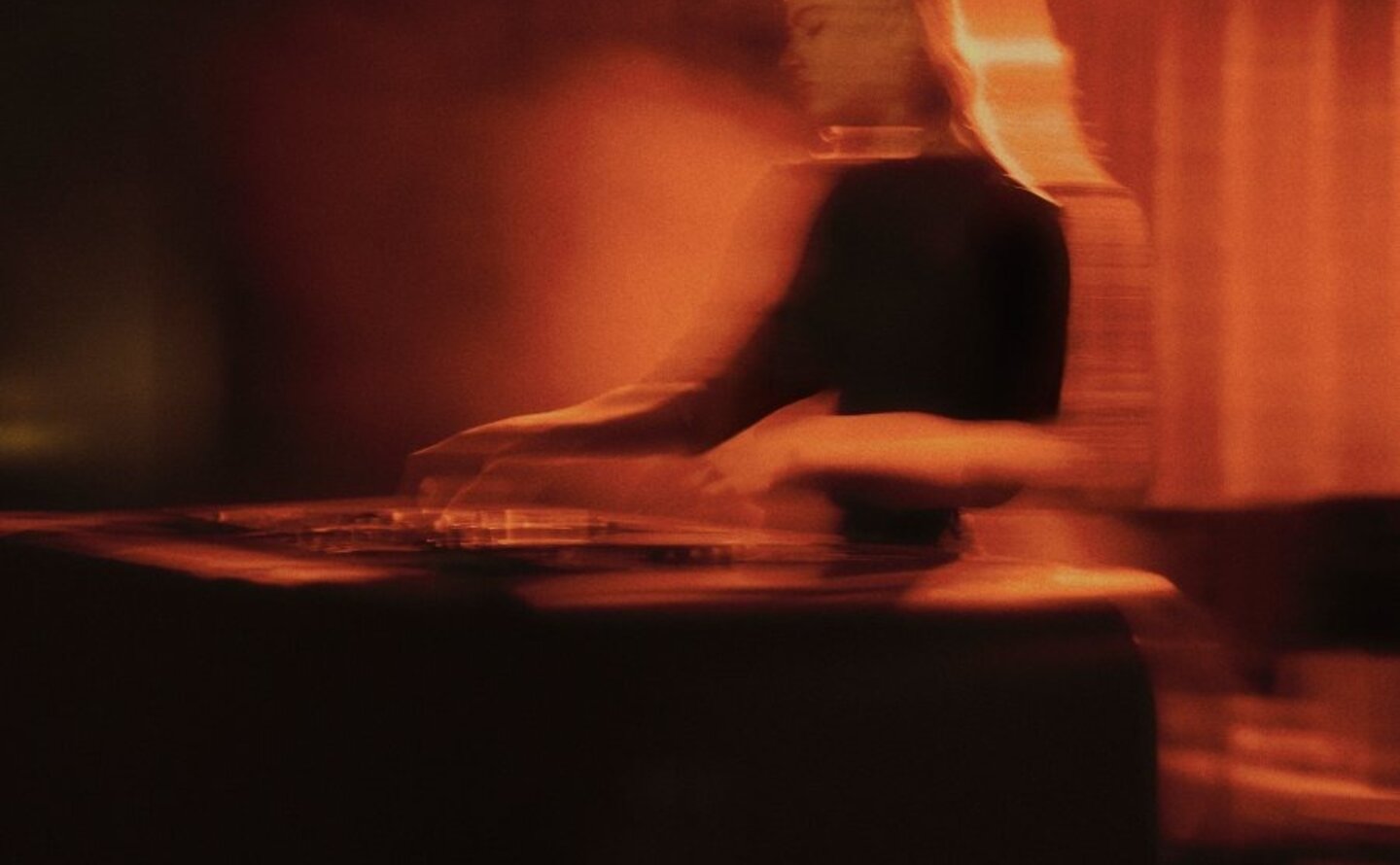 DJ performing at Aman New York's jazz club, bathed in warm amber lighting.