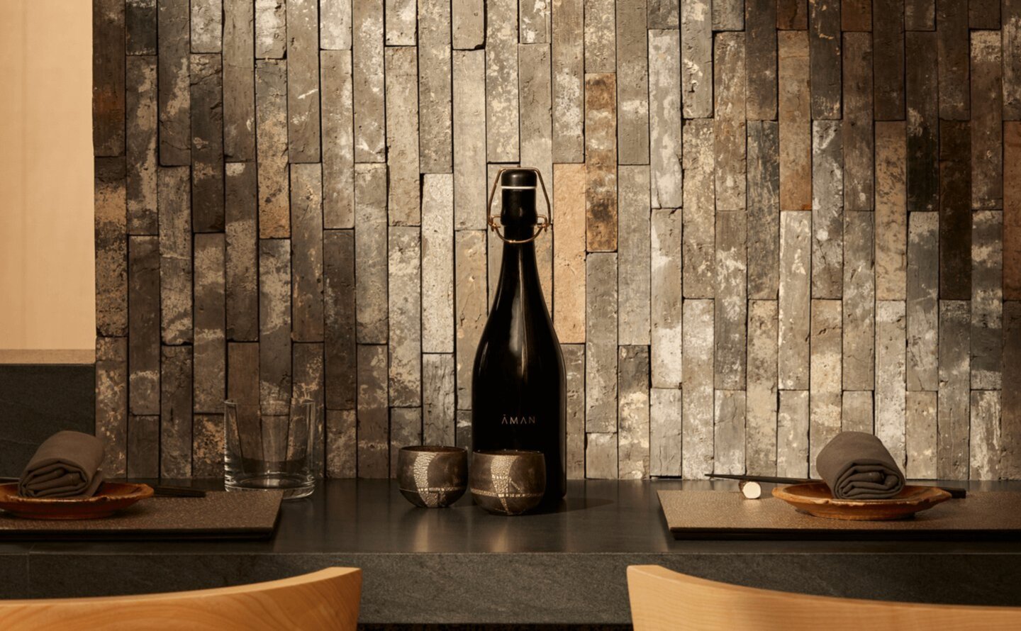 Akari installation with champagne bottle at Aman New York, featuring geometric tilework backdrop.