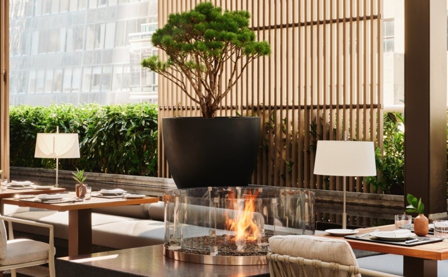 Arva Garden Terrace dining room at Aman New York, with tables, chairs, and a sculptural tree centrepiece.
