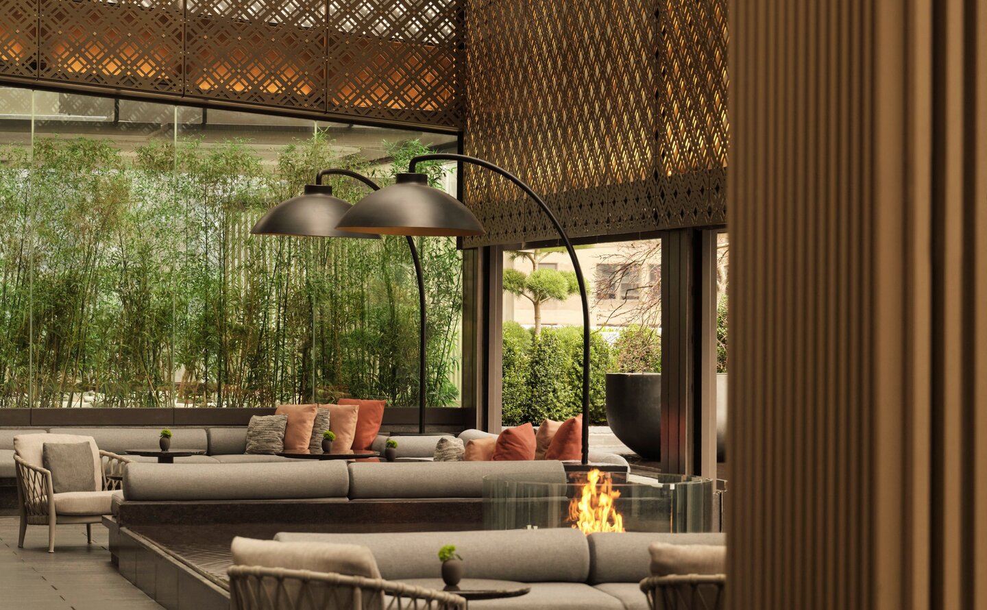 Garden Terrace lounge at Aman New York with woven screens, seating areas, and views to greenery.
