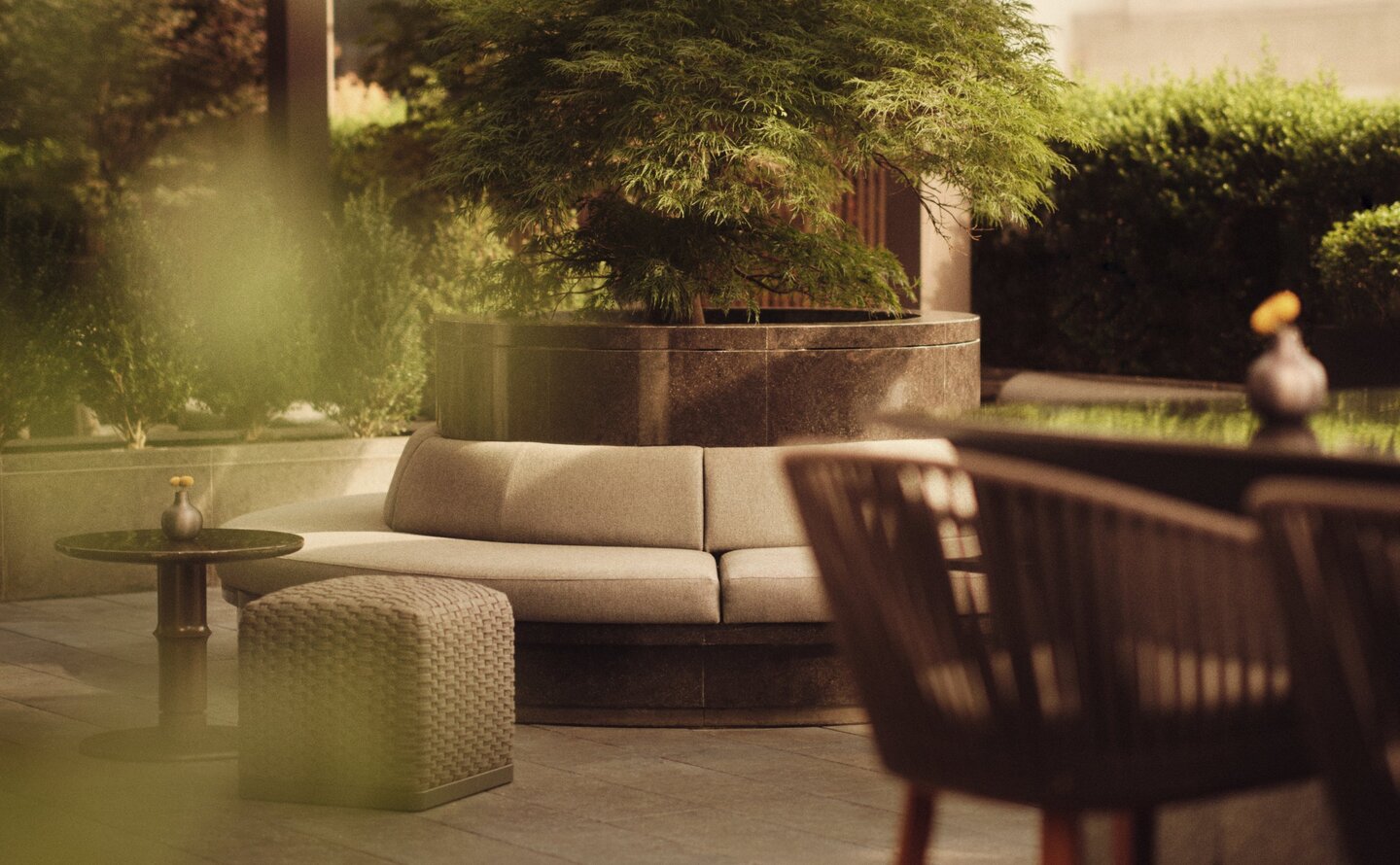 Rooftop terrace at Aman New York with seating area and greenery at dusk.
