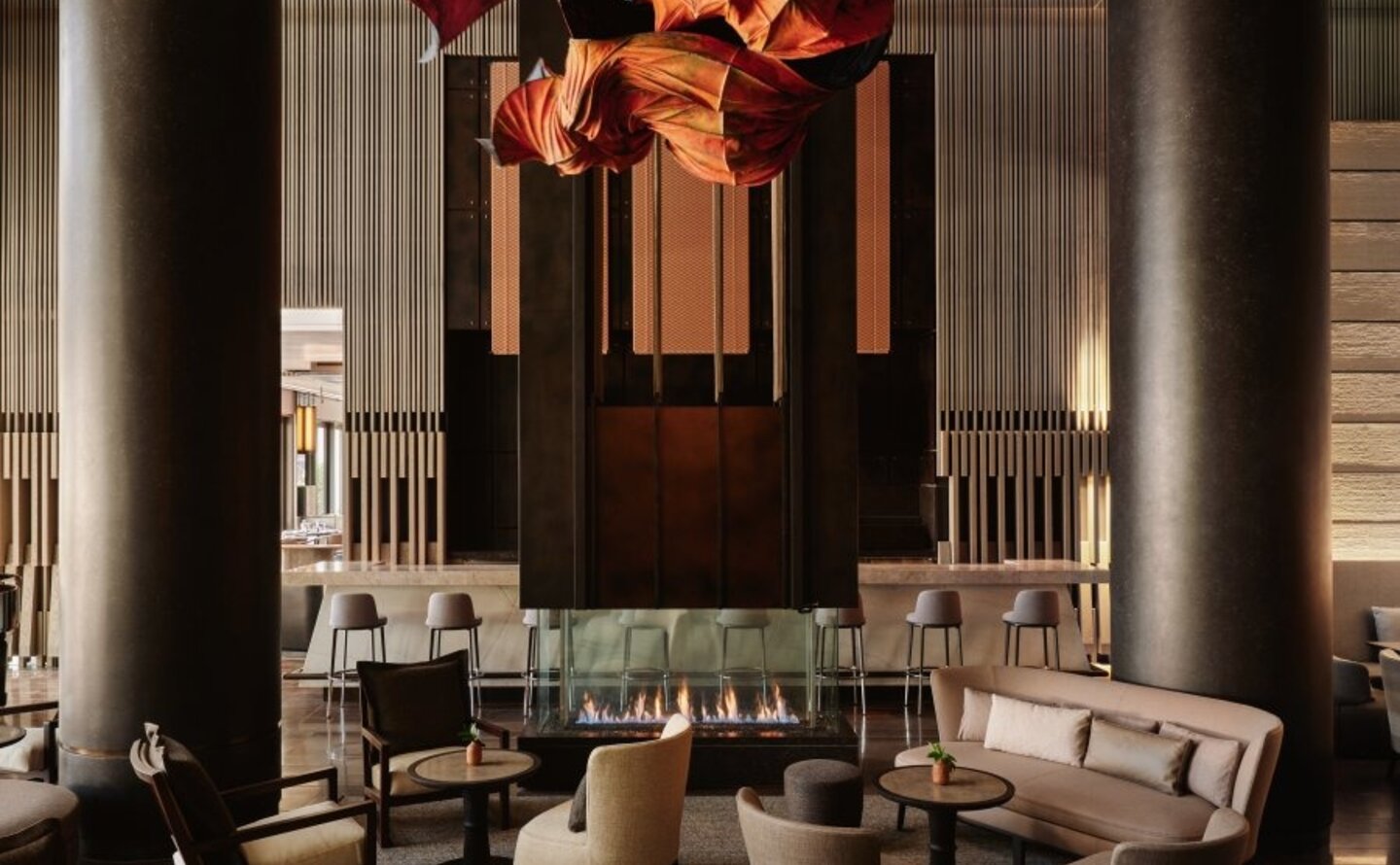 Aman New York's lounge interior with soaring columns, contemporary seating arrangements, and a striking amber-toned sculptural installation overhead.