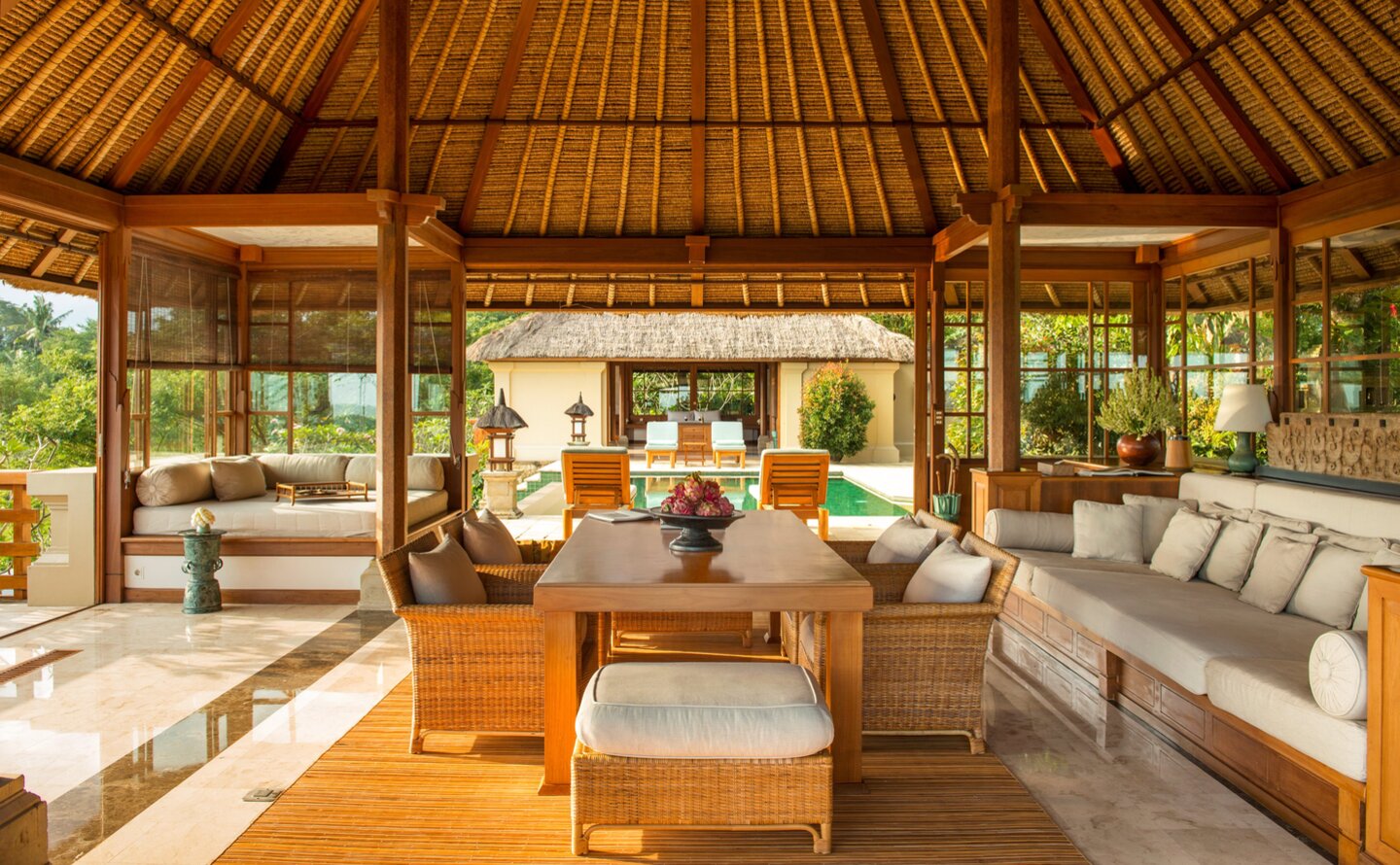 Three-bedroom villa living area at Amandari with wooden ceiling, cream furnishings and garden views.