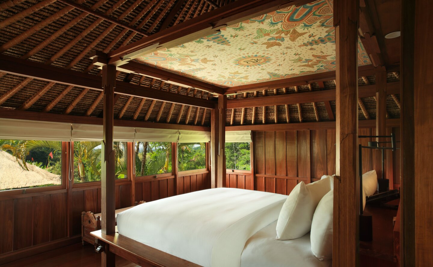 Bedroom in a duplex pavilion at Amandari, Indonesia, with a four-poster bed and wooden ceiling detail overlooking tropical gardens.