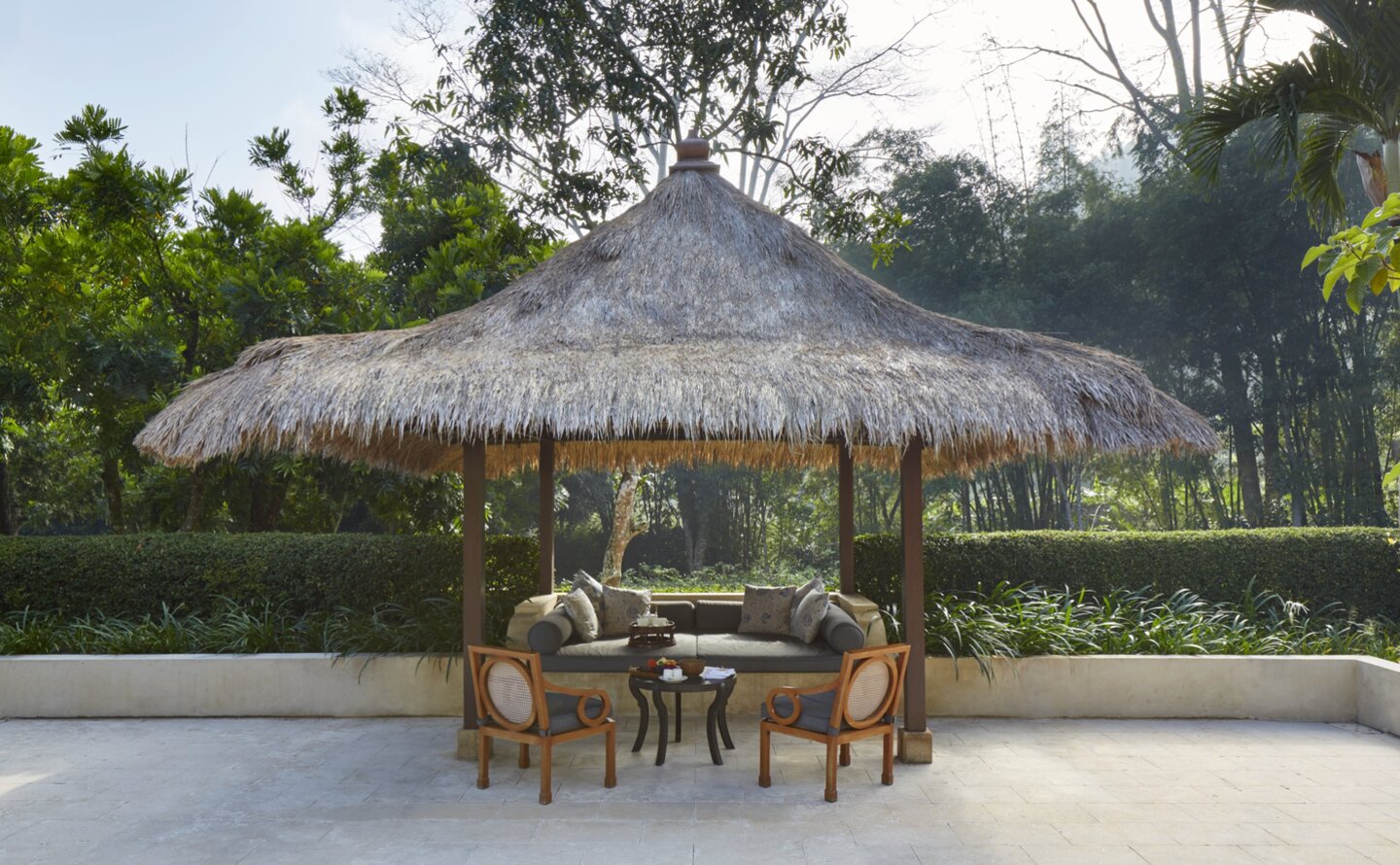 Garden pavilion with thatched roof at Amanjiwo, Indonesia, offering shaded seating amongst landscaped grounds.