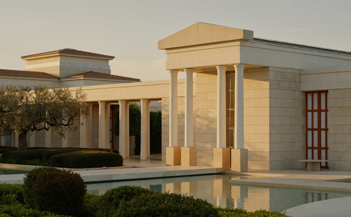 Amanzoe resort buildings reflected in still water at dusk, Greece.
