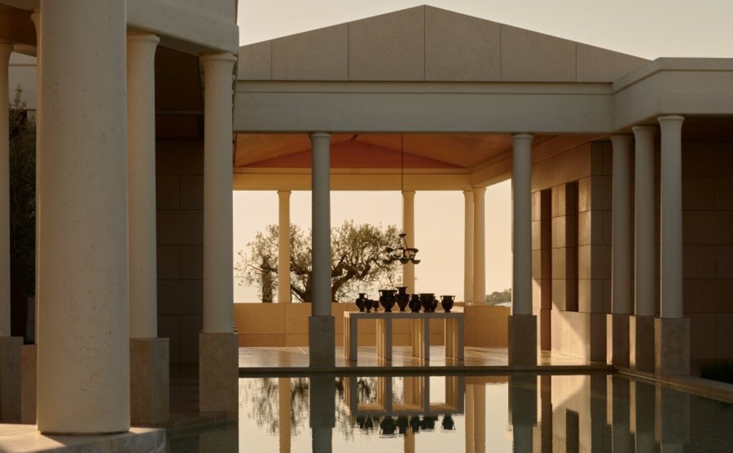 Amanzoe resort entrance at dusk, featuring illuminated wooden doors and columns framing the doorway.